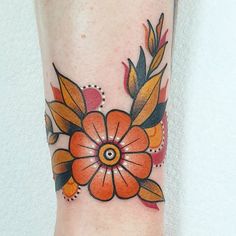 an orange flower tattoo on the left arm and leg, with leaves around it's center