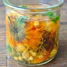 a jar filled with flowers sitting on top of a wooden table