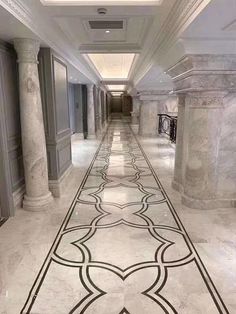 a long hallway with white marble floors and columns