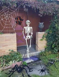 a skeleton and two spider webs in front of a house