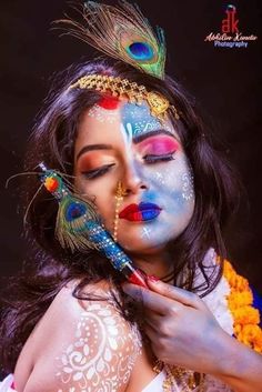 a woman with painted face and feathers on her head is holding a feather in her hand