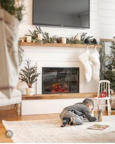 a young boy laying on the floor in front of a fireplace with stockings hanging from it