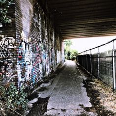 an alley with graffiti on the walls and fenced in area next to it,