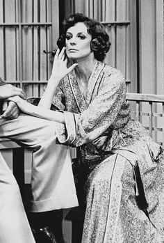 an old black and white photo of two women sitting on a bench talking to each other