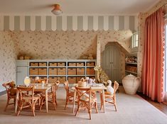 a room with striped walls and wooden furniture in the center is filled with small tables, chairs, and storage containers