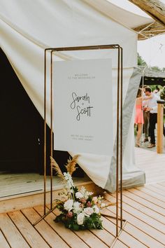 a sign that is on top of a wooden floor next to some flowers and plants