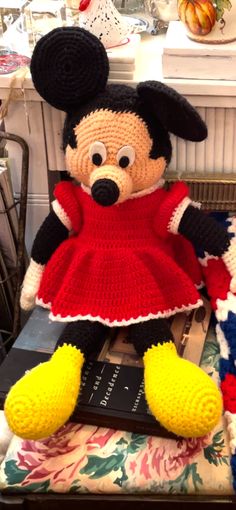 a crocheted mickey mouse doll sitting on top of a chair next to a book