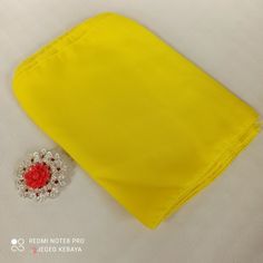 a yellow cloth with a red flower brooch on the side and a white background