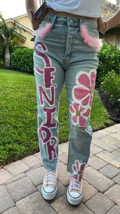 15 Cutest Senior Jeans Ideas We're Obsessing Over Right Now School Spirt Pants, White Senior Jeans Painted, Maroon Senior Overalls, Senior 2023 Jeans, Spirit Week Jeans Ideas, Senior Jeans Painted 2023 Pink, Senior Jeans 2023, Pink Out Jeans Painted, Painted Jeans Seniors