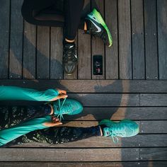 two people standing next to each other on a wooden floor with their feet in the air