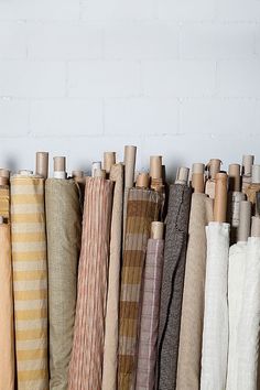 many different colored umbrellas lined up against a white brick wall with wooden pegs