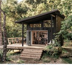 a small cabin in the woods with stairs leading up to it's door and porch