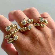 a person's hand with some gold rings on it and diamonds in the middle