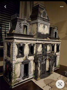 a doll house is shown on a table with papers and pentagrams next to it