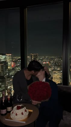 a man and woman kissing in front of a cityscape at night with wine