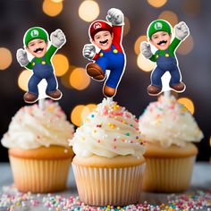 three cupcakes with super mario and luigi on top, surrounded by sprinkles