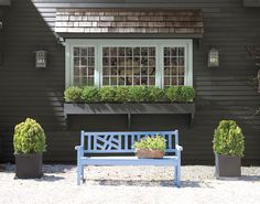 a blue bench sitting in front of a green house with plants growing out of it