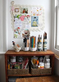 a wooden table topped with lots of crafting supplies next to a wall covered in pictures