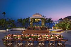 an outdoor wedding set up with flowers and candles on the table in front of it