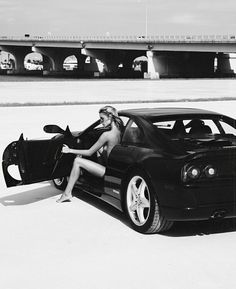 a woman sitting on the hood of a sports car