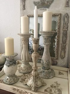 three candles are sitting on top of a dresser in front of a mirror with an ornate frame