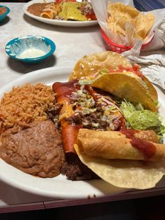 a white plate topped with lots of food next to tacos and corn tortillas