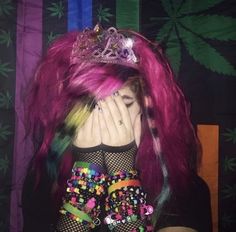 a woman with pink hair wearing a tiara and holding her hands to her face