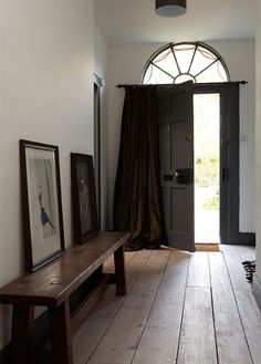 an open door with a bench in front of it and pictures hanging on the wall