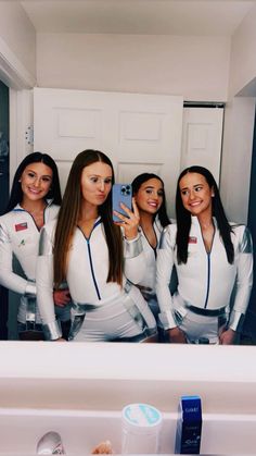 four beautiful women in white outfits taking a selfie