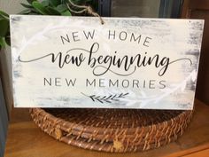 a wooden sign that says new home, new beginning and new memories on it next to a wicker basket