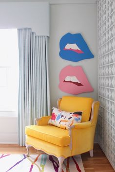 a yellow chair sitting in front of a wall with three different colored lips on it