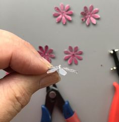 a person is holding some tiny flowers in their left hand and scissors on the right