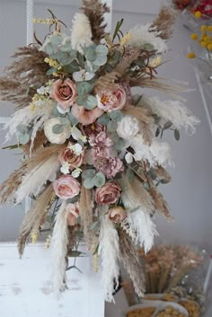 an arrangement of dried flowers and feathers hanging from a door