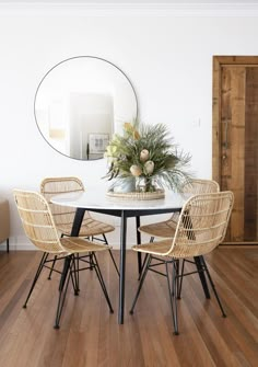 a dining room table with chairs and a mirror on the wall