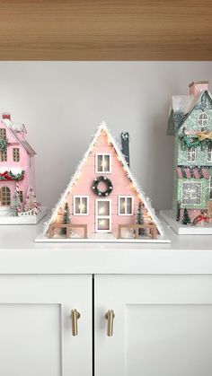 three christmas houses on top of a white cabinet