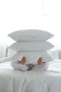 a person laying in bed with four pillows stacked on top of each other