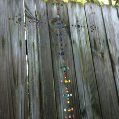 a wooden fence with beads on it and trees in the background