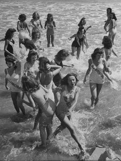 a group of women in bathing suits running into the ocean