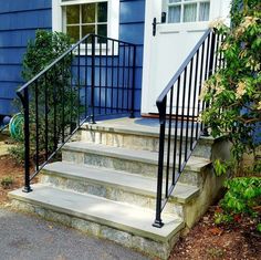 a set of stairs leading up to a blue house with white door and window in the background