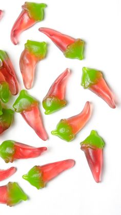 some red and green gummy bears on a white surface