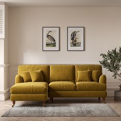 a living room with two framed pictures on the wall and a yellow couch in front of it