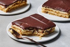 three pieces of cake sitting on top of white plates with chocolate frosting and a spoon