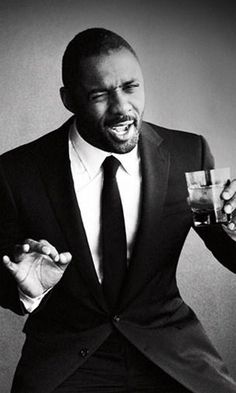 a black and white photo of a man in a tuxedo holding a drink