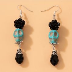 the skull earrings are decorated with black and blue beads, skulls and roses on them