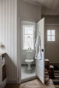 an open door leading to a bathroom with a toilet and sink in the corner next to a window