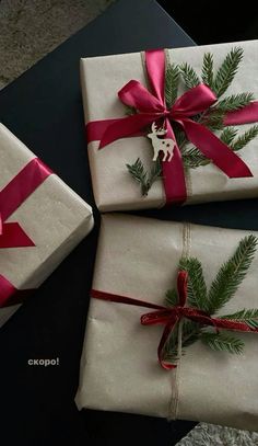 three wrapped presents with red ribbon and bows on top of each other, sitting on a table