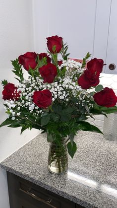 a vase filled with red roses sitting on top of a counter