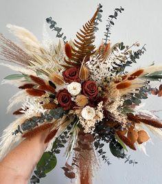 a person holding a flower arrangement in their hand