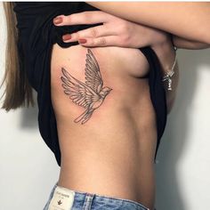 a woman's stomach with a bird tattoo on her side and the bottom part of her body