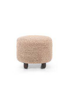 the foot stool is made out of sheepskin and has black legs, with a light brown